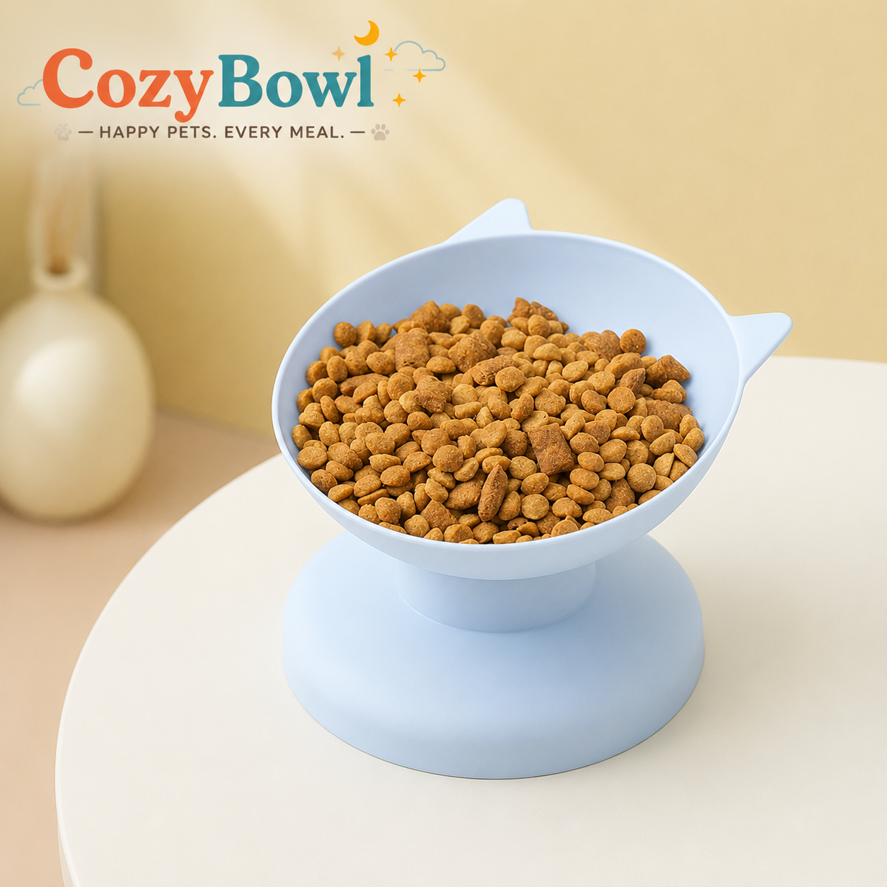 A light blue elevated pet bowl filled with dry kibble, shown on a round pedestal against a warm beige background. The Cozy Bowl brand logo appears in the upper left.
